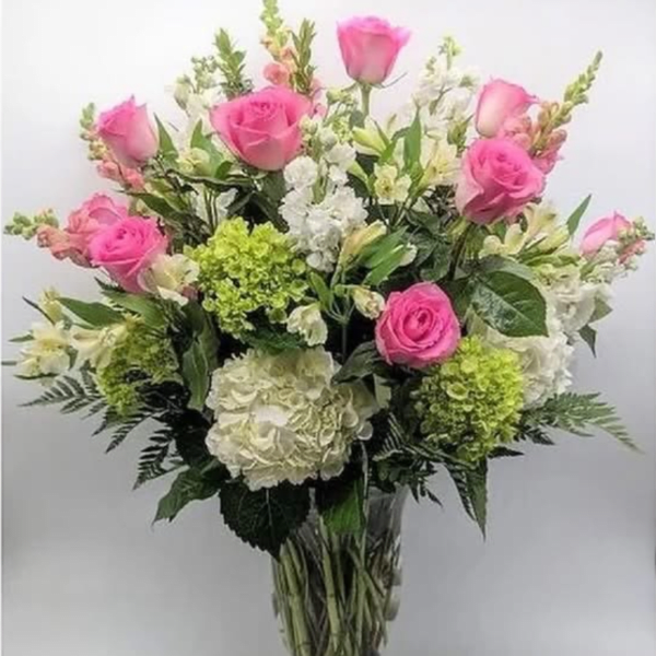 Bouquet of pink roses, white hydrangeas, and white flowers in a clear vase