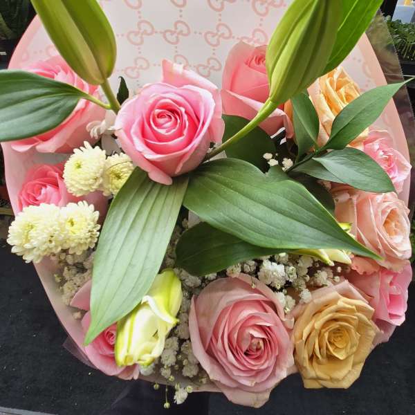 Pink and peach rose bouquet with lily buds and white filler flowers