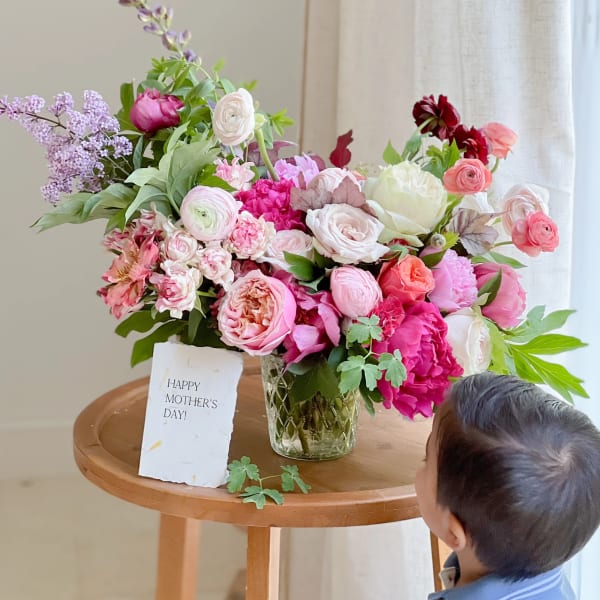 Mixed pink and white flower arrangement in a glass vase with a Mother's Day card