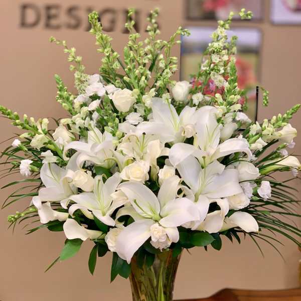 White lilies and roses arranged in a clear glass vase