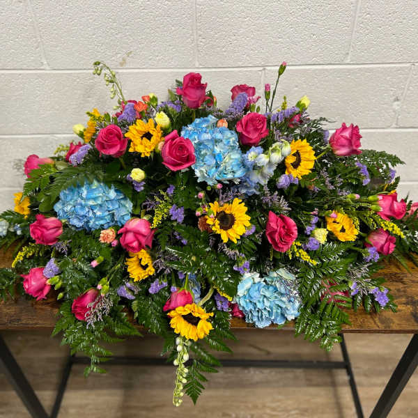 Large floral arrangement with pink roses, blue hydrangeas, and yellow sunflowers