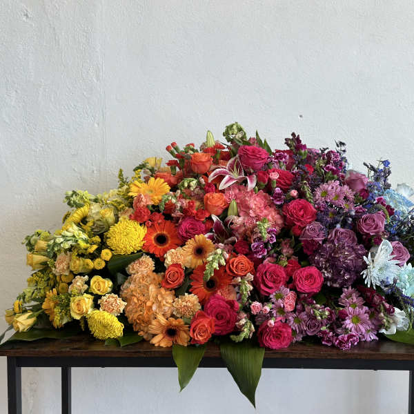Large multicolored floral arrangement with roses, gerberas, and chrysanthemums on a table