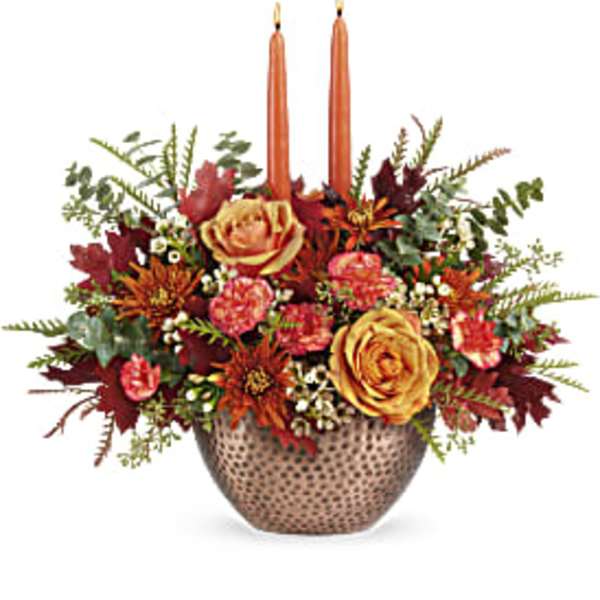 Autumn floral arrangement with two orange candles in a textured vase