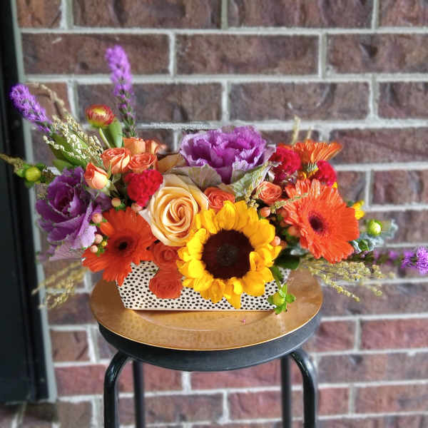 Colorful mixed flower arrangement in a white polka-dot rectangular container