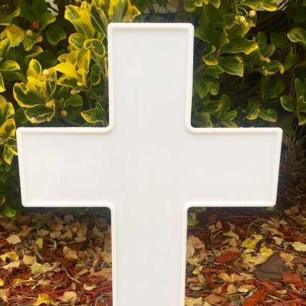 White cross-shaped memorial sign on a stake outdoors