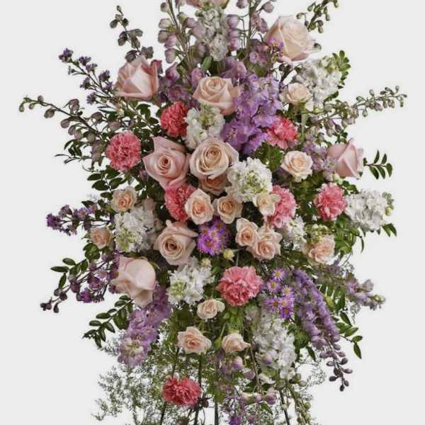 Tall standing spray of pink roses, carnations, and purple flowers