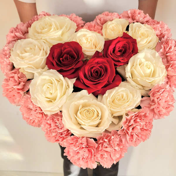 Heart-shaped bouquet of red and white roses edged with pink carnations