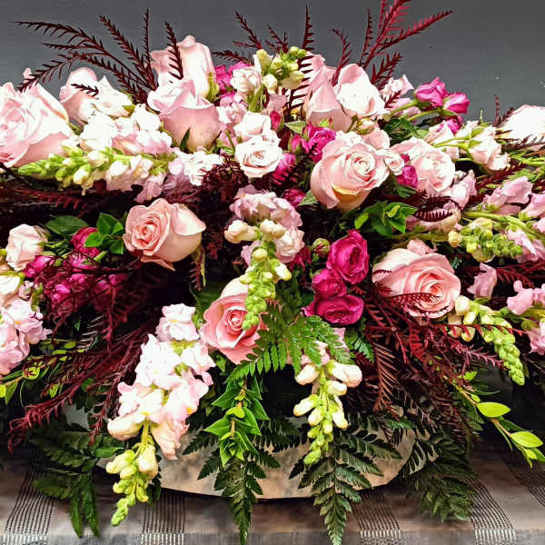 Large pink rose arrangement with burgundy foliage and white accent flowers