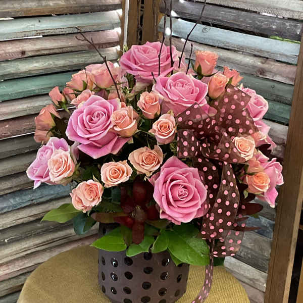 Pink and peach roses arranged in a polka-dot vase with ribbon