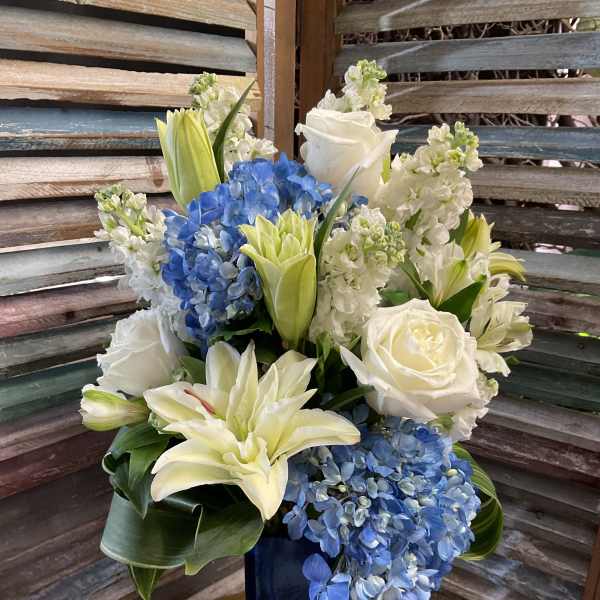 Blue and white floral arrangement in a tall dark vase