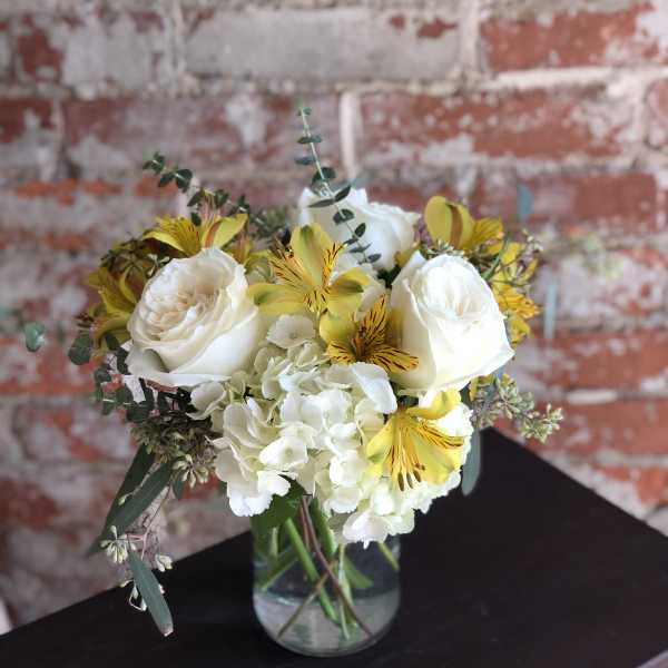 White roses and yellow alstroemeria in a glass vase