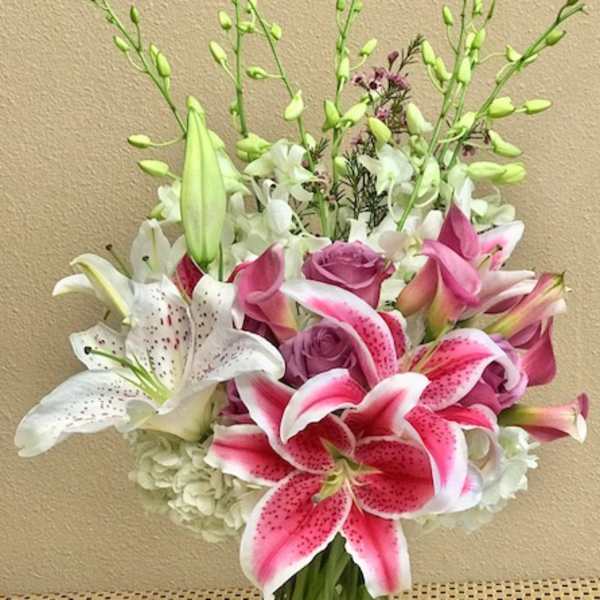 Pink and white lilies with roses in a glass vase