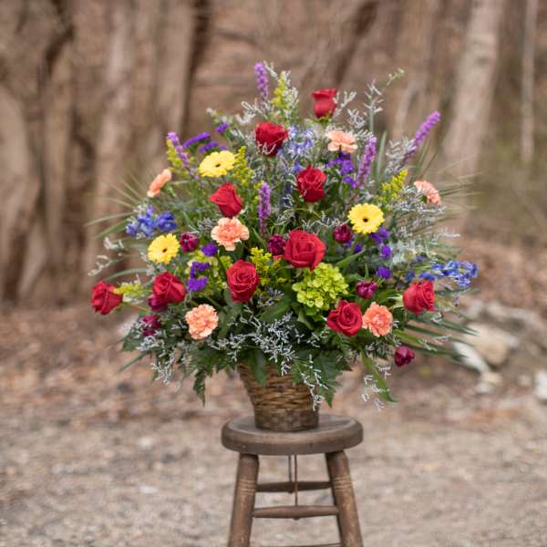 Mixed bouquet of roses, daisies, and carnations in a woven basket
