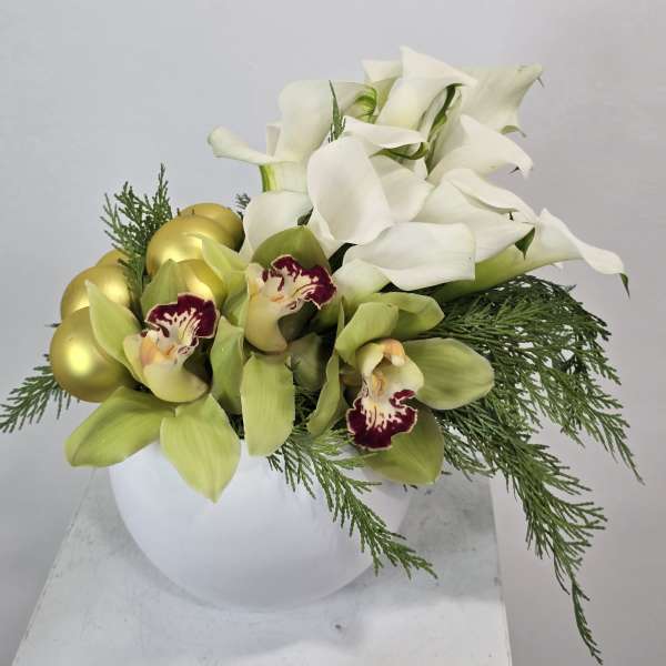 White calla lilies and green orchids in a white vase with gold eggs