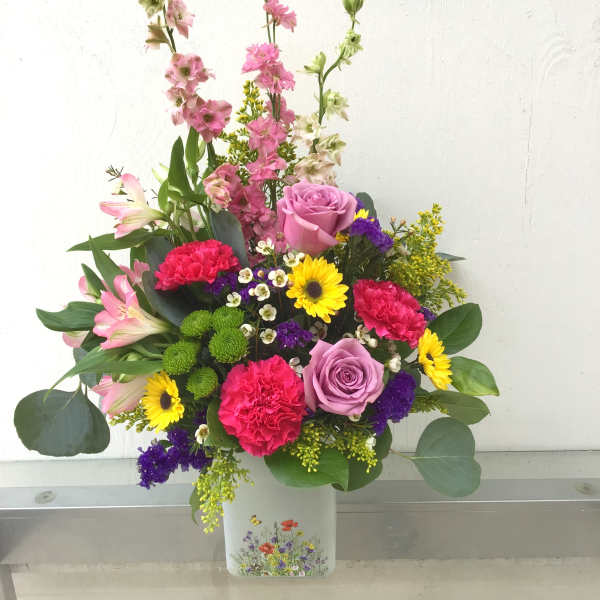 Mixed pink and yellow flowers arranged in a white vase