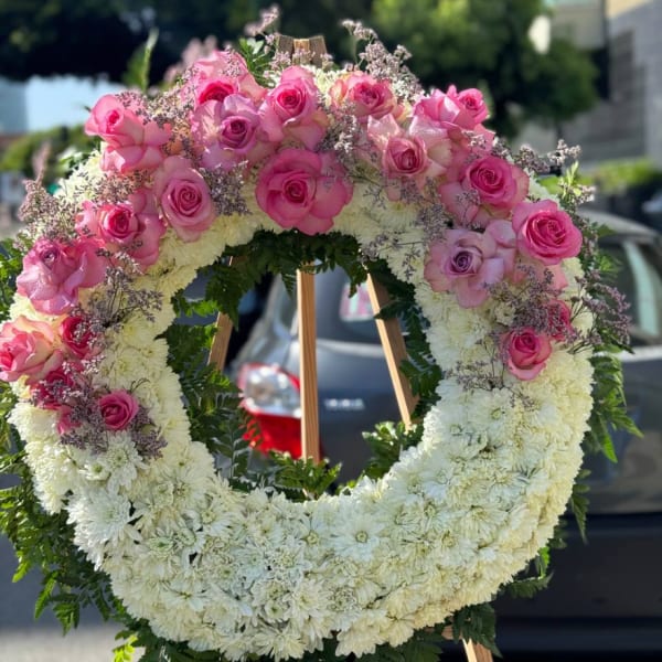 Large pink and white floral wreath on a wooden easel