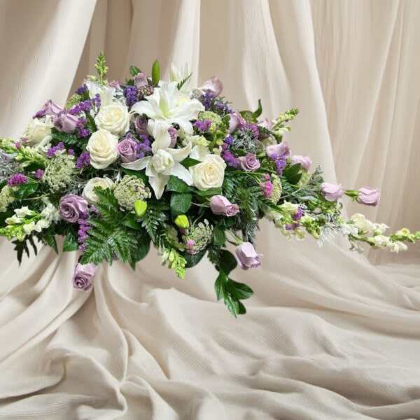 Low floral arrangement of white lilies, roses, and lavender blooms