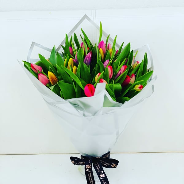 Bouquet of multicolored tulips wrapped in white paper