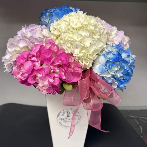 Colorful hydrangea bouquet in a white box with a pink ribbon
