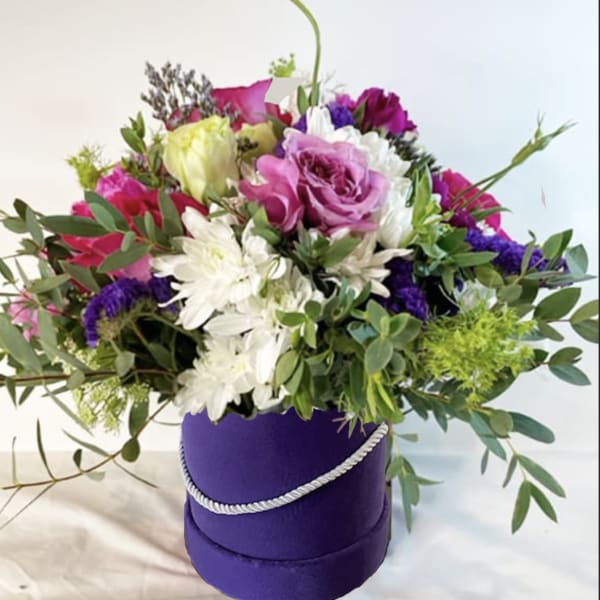 Mixed bouquet in a purple hatbox with pink, white, and purple flowers