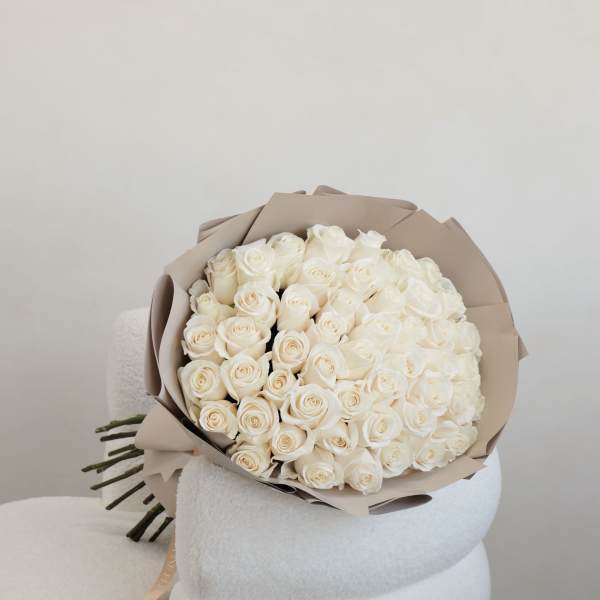 Bouquet of white roses wrapped in beige paper