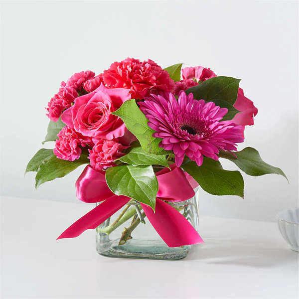 Pink mixed flower bouquet in a glass vase with a ribbon