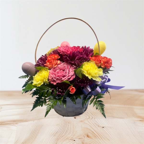 Basket arrangement of pink, yellow, and purple flowers with decorative eggs