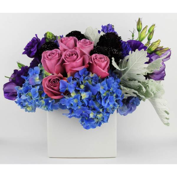 Pink roses and blue hydrangeas in a white square vase