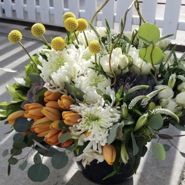Bouquet of white chrysanthemums and orange tulips in a dark vase
