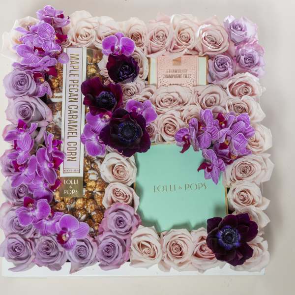 Floral gift box with pink and lavender roses and purple orchids around candy boxes