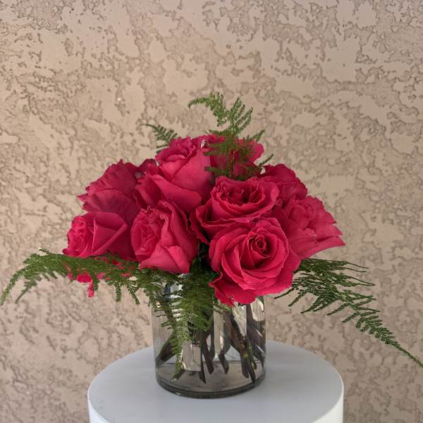 Pink rose bouquet in a clear glass vase with fern accents