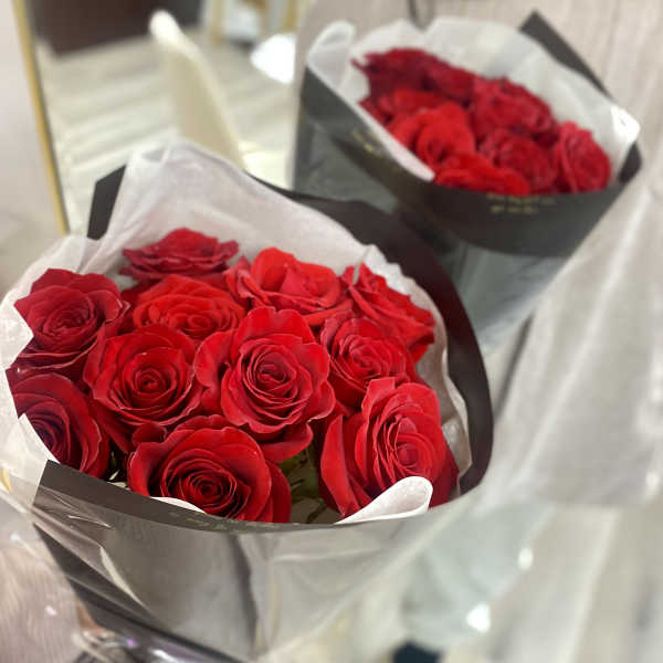 Two bouquets of red roses wrapped in black and white paper
