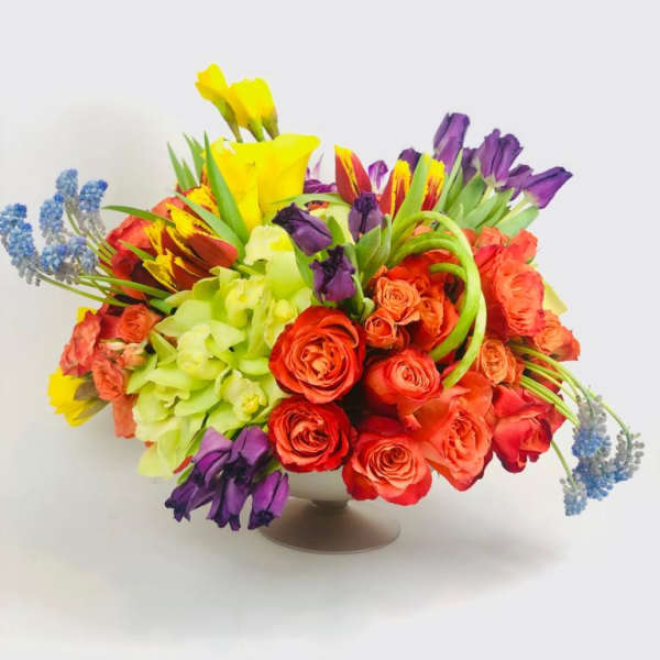 Colorful bouquet of roses, tulips, and orchids in a low vase