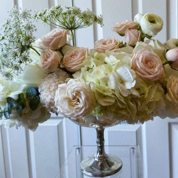Blush roses and cream hydrangeas in a silver pedestal vase