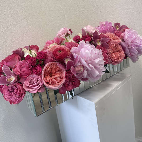 Pink and lavender floral arrangement in a mirrored rectangular vase
