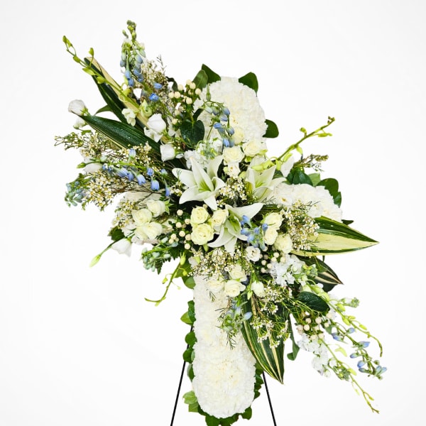 White floral standing spray on an easel with blue ribbon bows