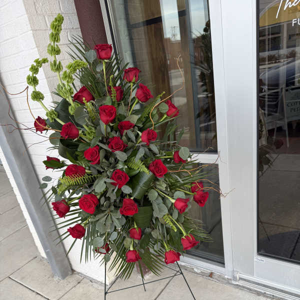 Tall standing arrangement of red roses with greenery on a metal easel