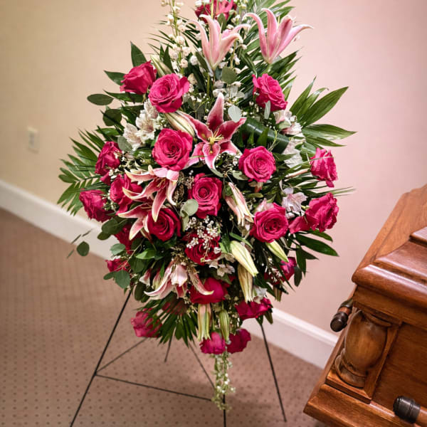 Standing floral spray with pink roses and lilies on a black easel