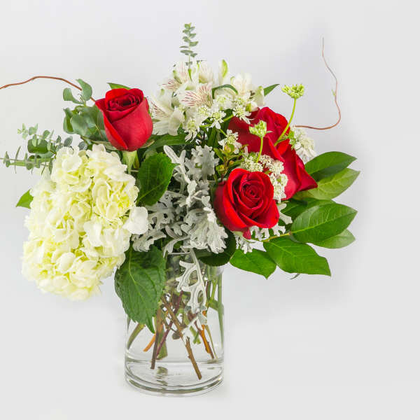 Red roses and white hydrangea in a clear glass vase