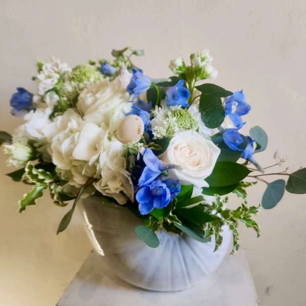White and blue floral bouquet in a wrapped container