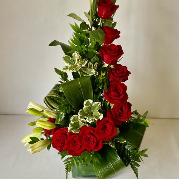 Tall arrangement of red roses and white lilies in a glass vase