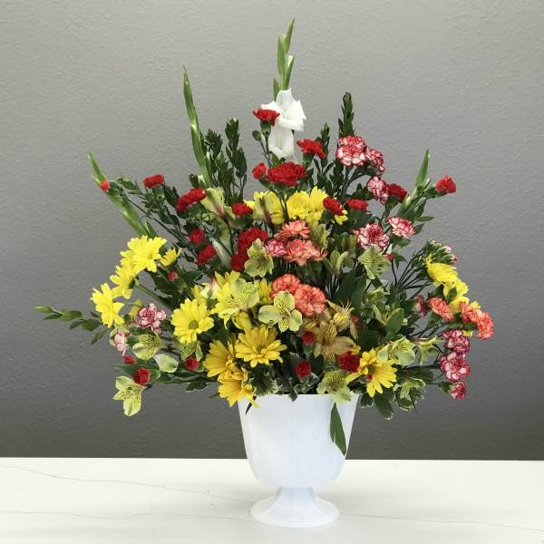 Colorful mixed flower arrangement in a white pedestal vase