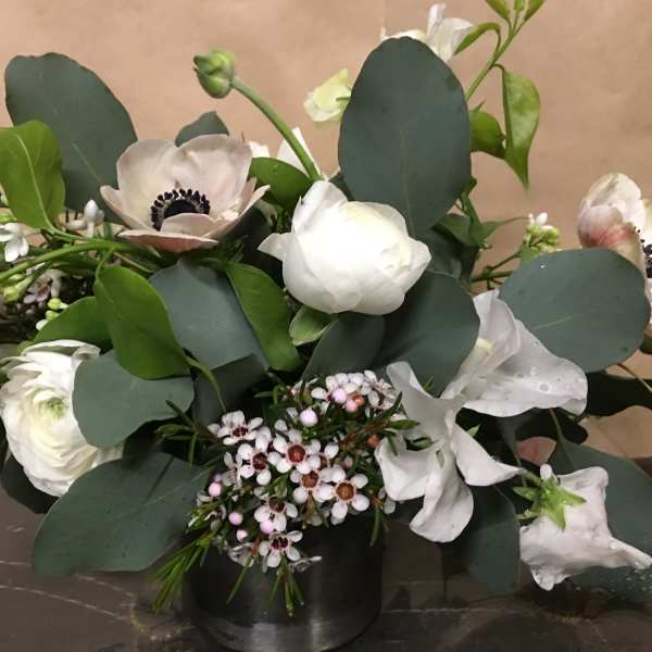 White anemones and ranunculus in a low black vase