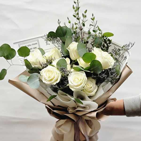 Bouquet of white roses with eucalyptus in tan wrapping