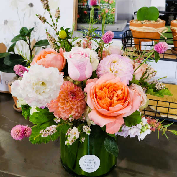 Mixed pink and peach flowers arranged in a green glass vase