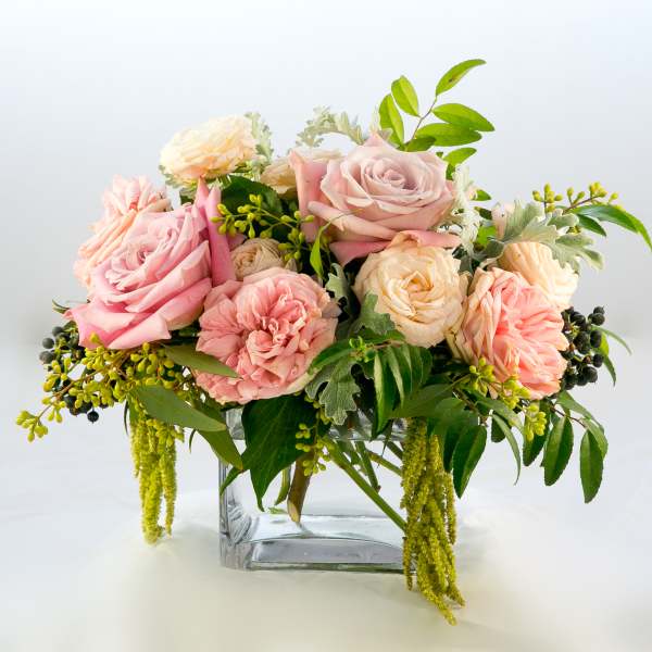 Pink and cream roses arranged in a clear glass vase