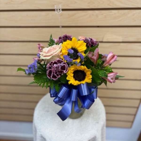 Mixed bouquet with sunflowers, roses, and alstroemeria tied with a blue ribbon
