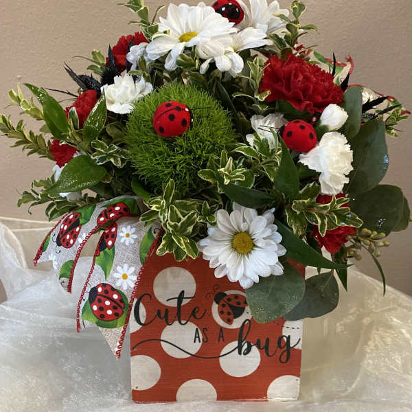 Bouquet of red and white flowers in a decorated gift box with ladybug accents