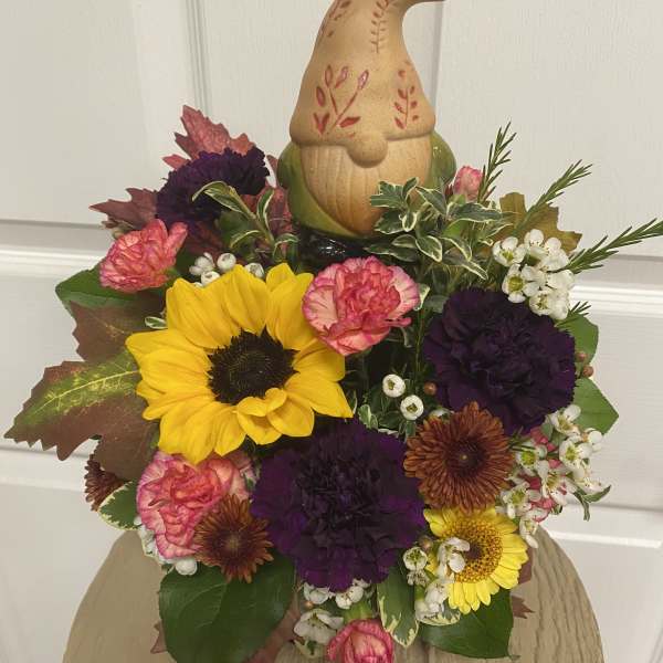 Fall floral arrangement with sunflowers, carnations, and a decorative gnome topper