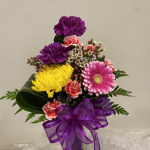 Colorful bouquet of carnations and a pink gerbera daisy in a glass vase